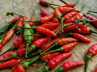 red bird's eye chilies on a wooden plank background