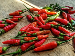 red bird's eye chilies on a wooden plank background