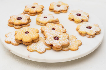 Flower shaped shortbread cookies filled with raspberry jam close up on white background