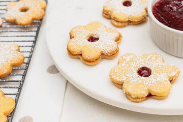 Flower shaped shortbread cookies filled with raspberry jam close up on white background