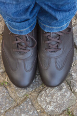 Brown leather shoes for men on footpath made of rocks or stones. Male footwear