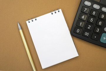 A notebook with a pen near a black calculator on a yellow background. Business and financial concept