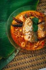Top view of spicy and hot king fish curry with herb and chili on wooden table, Thai food made from coconut milk and egg pant whit herbs, Fish curry