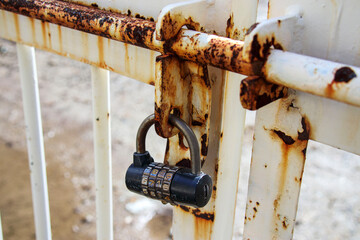 錆びた柵に付けられた南京錠（ダイヤル錠）
