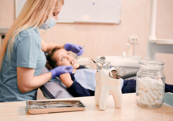 Close up of dental explorers, mirrors, scissors and scalers with pediatric dentist and little girl...