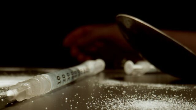 MACRO: Drug addiction. Camera moves by syringe. Sprinkled white powder. Human hand on background.