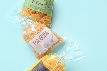 Bags with uncooked pasta on color background