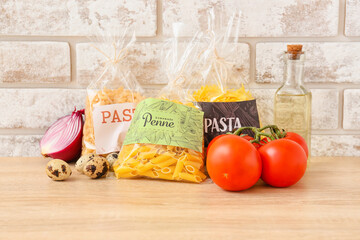 Bags with uncooked pasta, quail eggs and vegetables on kitchen table