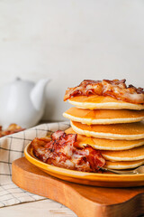 Plate with tasty pancakes and fried bacon on table