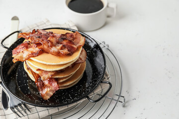 Plate with tasty pancakes and fried bacon on table