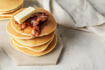 Tasty pancakes with butter and fried bacon on table