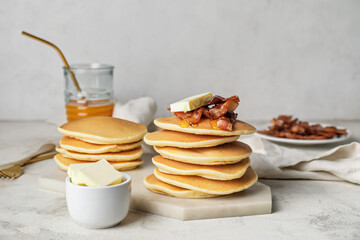 Tasty pancakes with butter and fried bacon on table