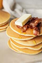 Tasty pancakes with butter and fried bacon on table
