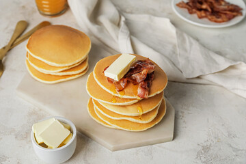 Tasty pancakes with butter and fried bacon on table