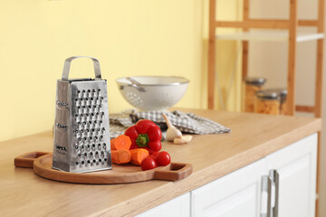 Grater, cutting board and vegetables on kitchen counter