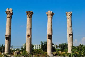 Fototapeta na wymiar Corinthian columns of Roman colonnade in Mersin at the site of Soli Pompeipolis ancient city with distance new urban buildings background. Mersin Turkey. 