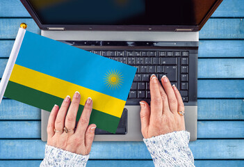 woman hands and flag of Rwanda on computer, laptop keyboard
