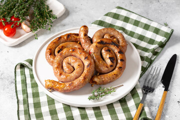 Spiral smoked sausages on a serving Board on a light gray table. Spiral sausages. Homemade meat...