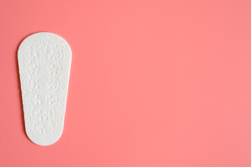 one pure empty women's disposable daily menstrual sanitary pad or napkin on pink background