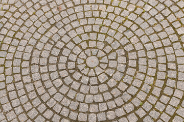 Old grey pavement of cobble stones in a circle pattern in an old medieval european town.