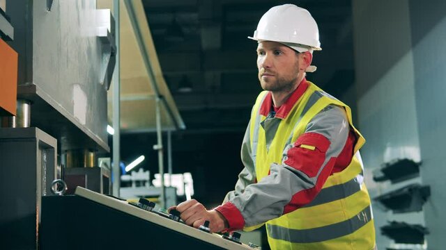 Male worker is managing a console of a factory machine