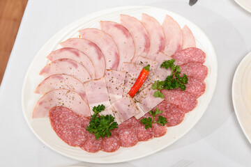 plate with different sliced sausage on table.