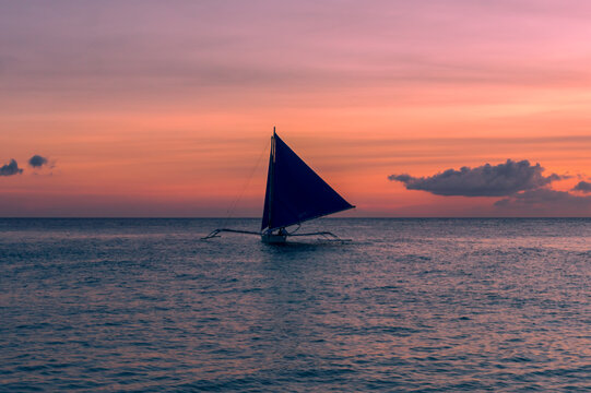 Beautiful sunset with a view of a local paraw saliboat in Boracy Island in the Philippines.  Travle and holiday.