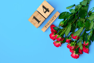 Wooden calendar and roses on blue background