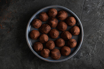 Truffle chocolate candy on ceramic plate top view.