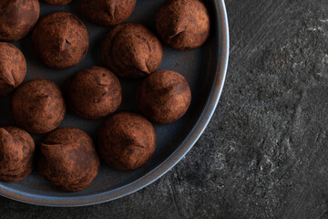 Truffle chocolate candy on ceramic plate top view.