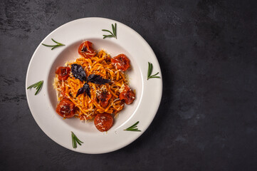 Pasta with cherry tomatoes, cheese and rosemary served on plate on dark textured background, top view, copy space