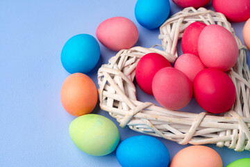 Colorful Easter eggs in decorative nest on blue background