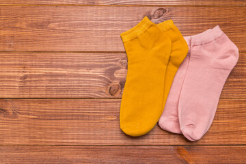 several pairs of multicolored new socks of different sizes stacked on a wooden background.