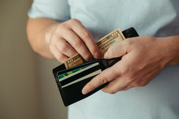 the man's hands take ten dollar bills from an empty wallet. Poverty concept, crisis. dismissal or...