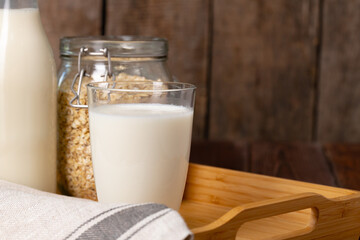 Glass of milk and oat flakes on wooden table