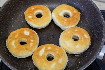 Homemade fried donuts on a frying pan.