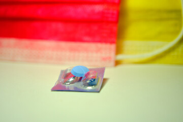Blue pills on the metallic color its packaging and colorful medical masks background.