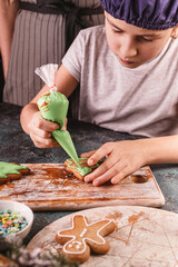 Girl decorate gingerbread cookies. Homemade traditional Christmas pastries. Delicious dessert. Hands of people close up. Vertical shot