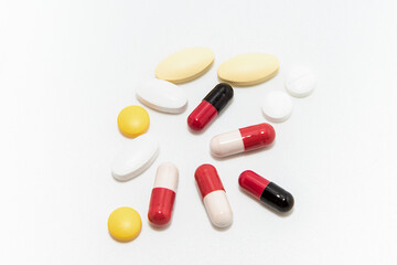 Red and white capsules  with some yellow and white tablet on white background