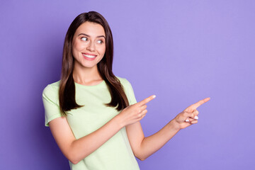 Photo portrait of cheerful happy girl smiling pointing with both hands looking at empty space isolated on bright violet color background
