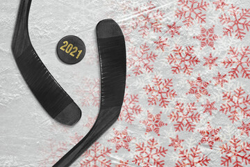 Two hockey sticks and a puck lying on the ice arena