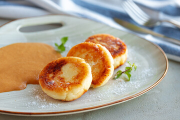 Russian cheesecakes served on plate with sauce