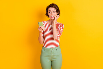 Photo of attractive person bite nail look phone very bad post isolated on vivid yellow color...