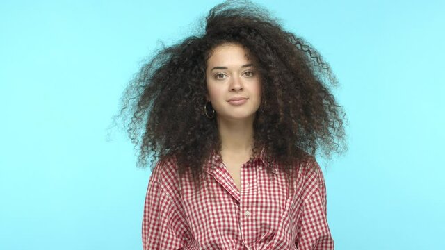 Slow motion of tensed and tired young woman holding hands on head, showing explosion gesture, say boom and stare distressed at camera, feeling pressure, standing over turquoise background