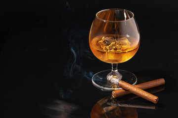 Glass of whisky and lighted cigar on black background