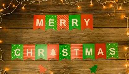 Merry Christmas wordmark on a background like a wooden table and a festive light border.