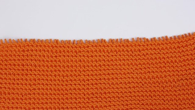 Stop motion close up animation unknitted texture. Details of orange knitted woolen fabric. 4K