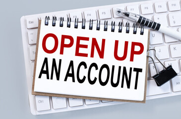 Fototapeta premium OPEN UP AN ACCOUNT, text on white paper on gray background on white keyboard