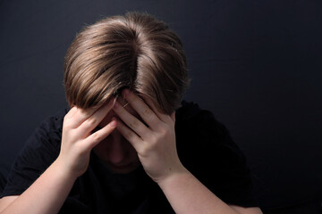 teenager sitting in a closed posture experiencing depression during COVID-19 lockdown