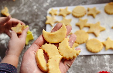 A cute 3-4 year old girl makes her own Christmas cookies. Family vacation at home during the holidays. Flour and dough. New Year's and Christmas. Child holding dough in his hands